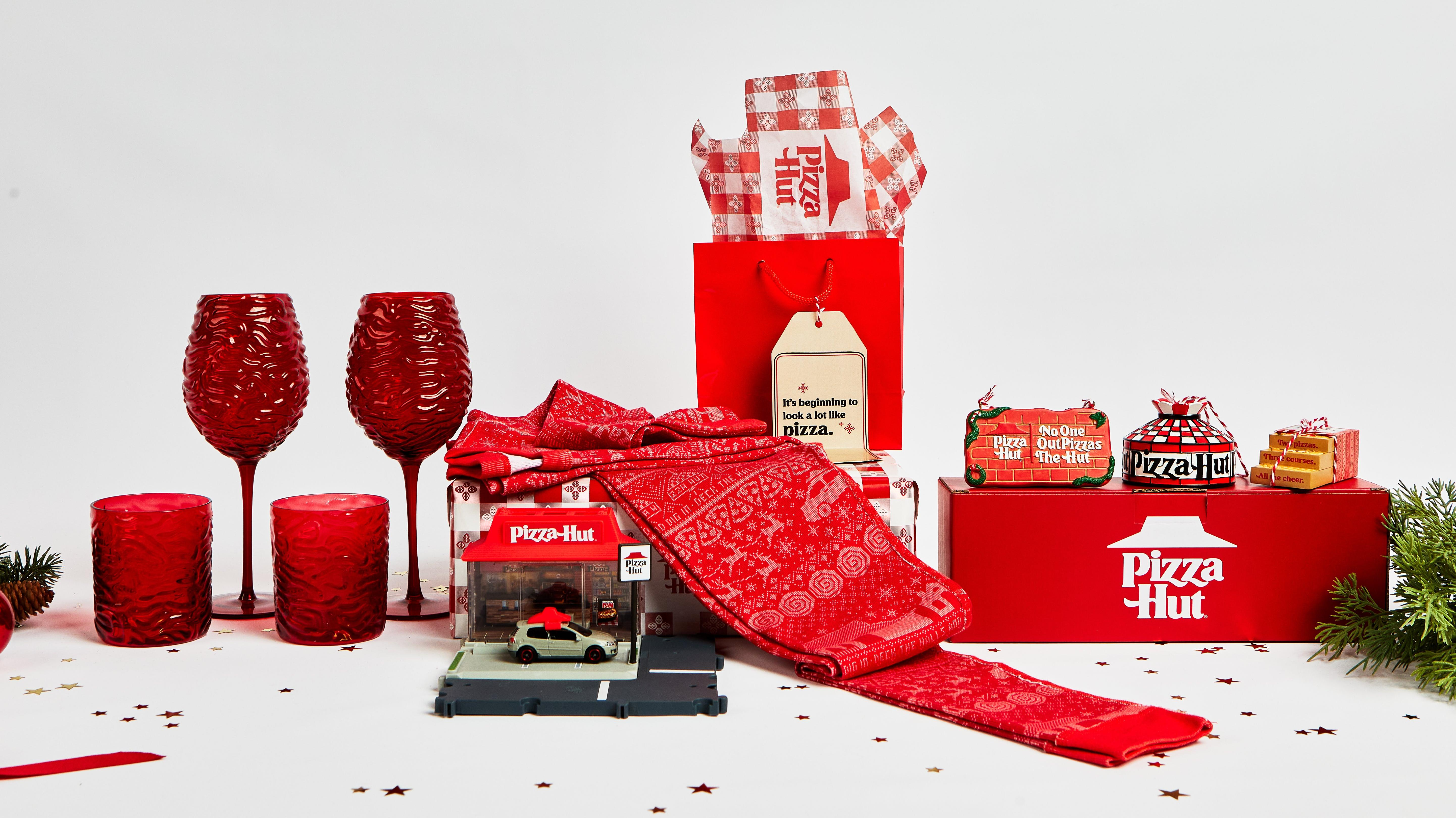 Pizza Hut 2021 holiday swag with wine glasses, rocks glasses, Matchbox set, ornaments, and pajamas