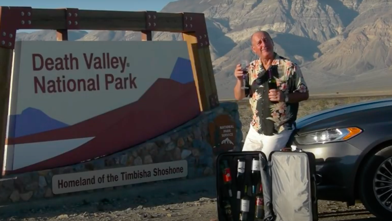 Man holds up glass of wine in front of 