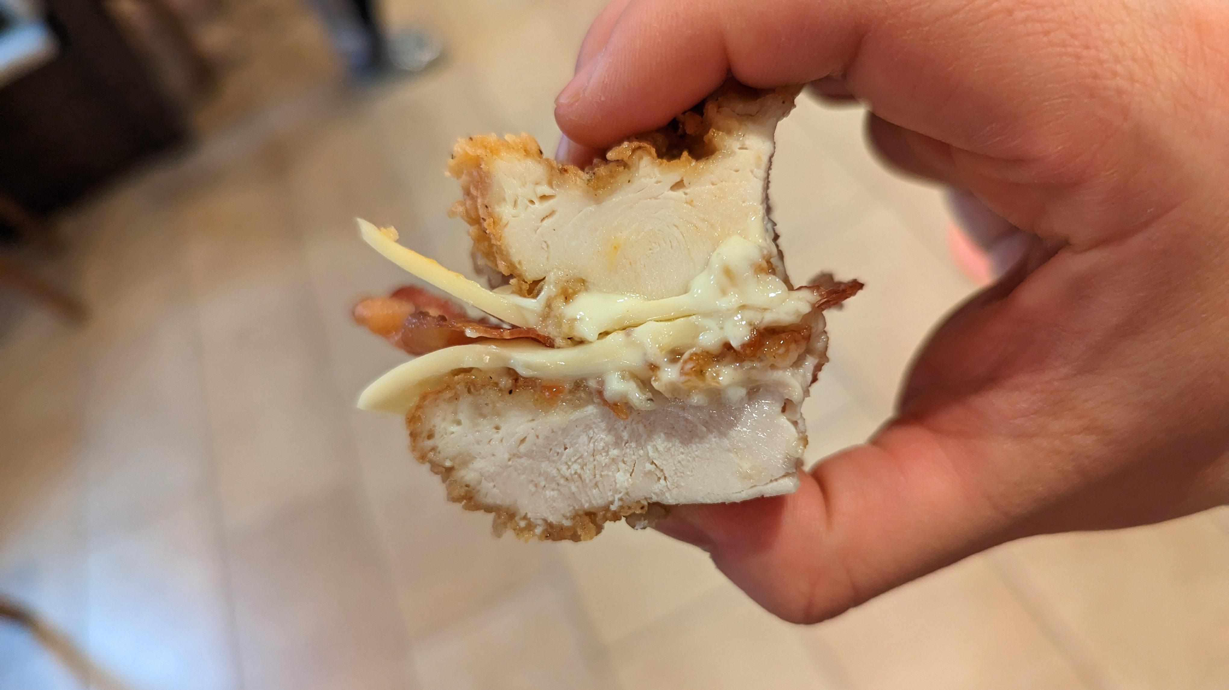 hand holding a cut piece of double down sandwich to show thickness of each chicken filet