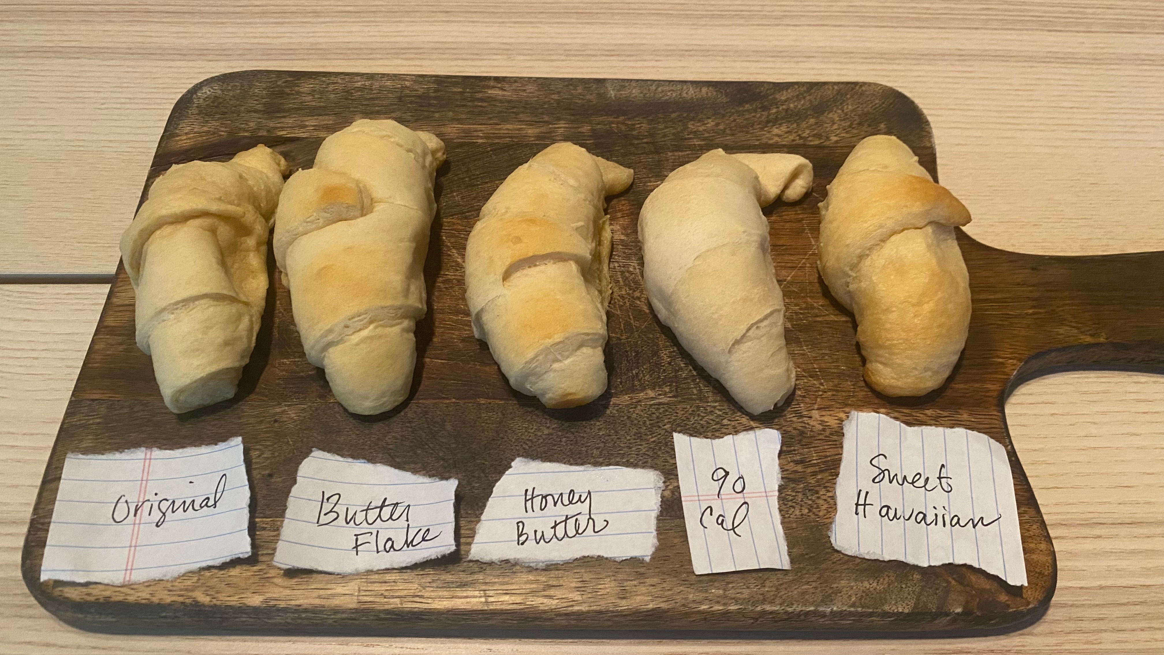 Baked crescent rolls are lined up on a cutting board.