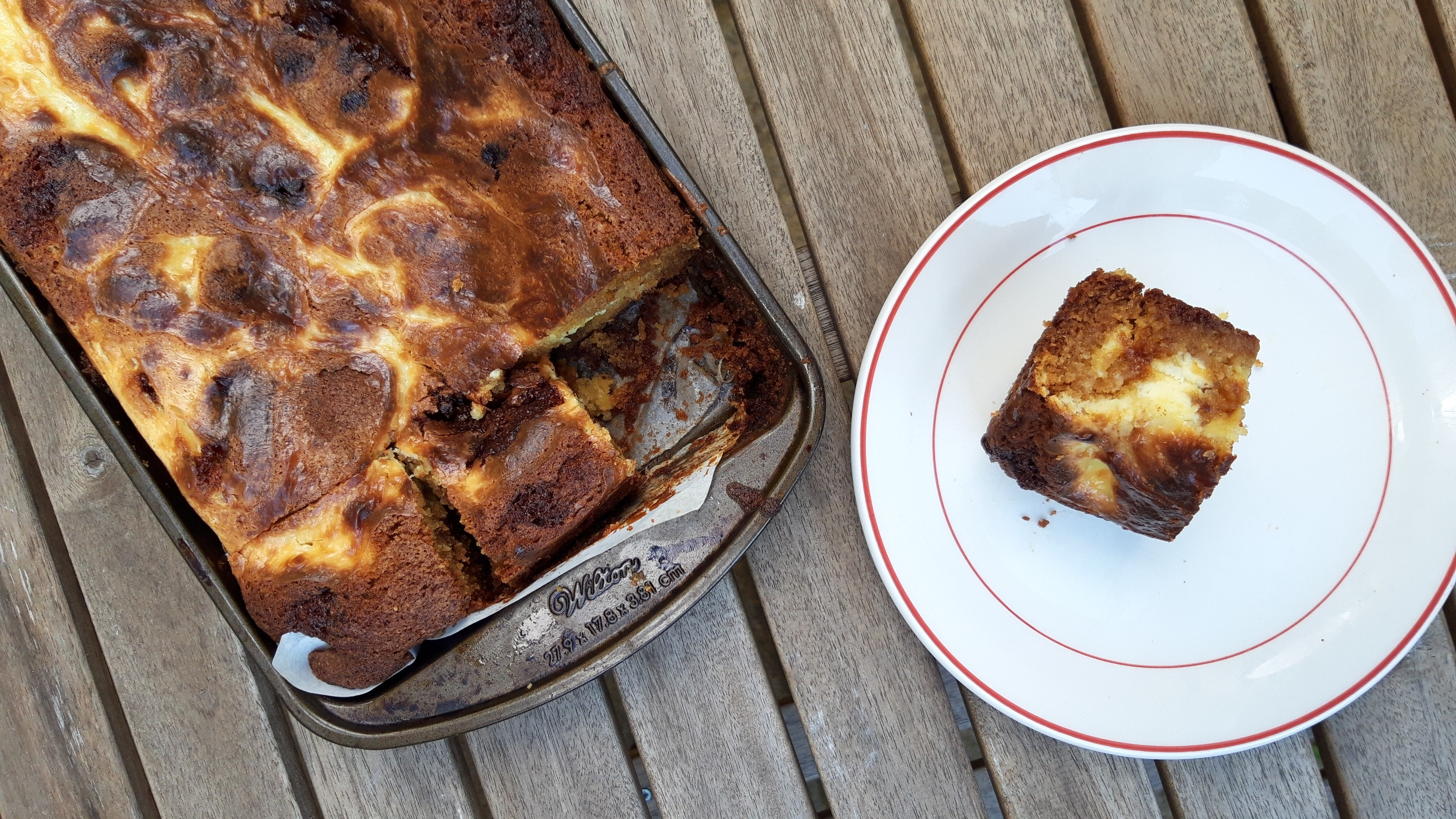 A pan of honeycomb blondies with one serving on a white plate to the side