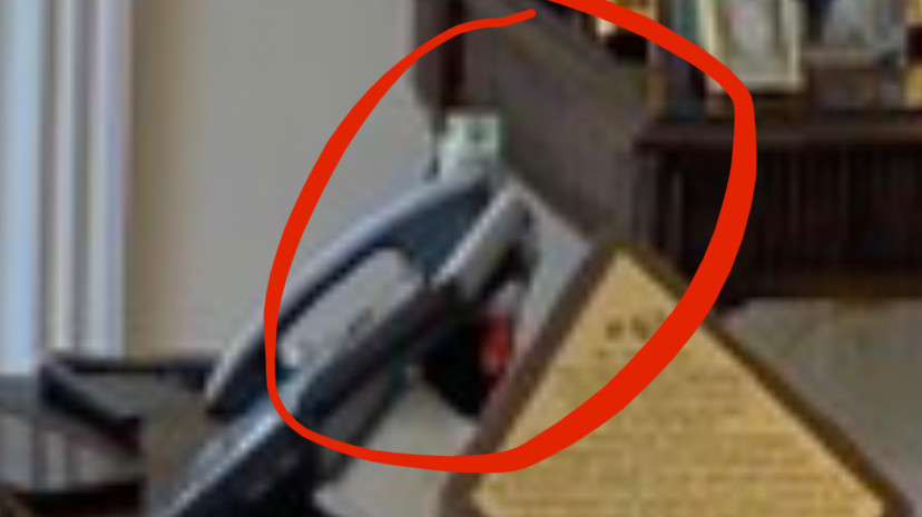 Close-up crop of photo in which bottle is visible behind phone