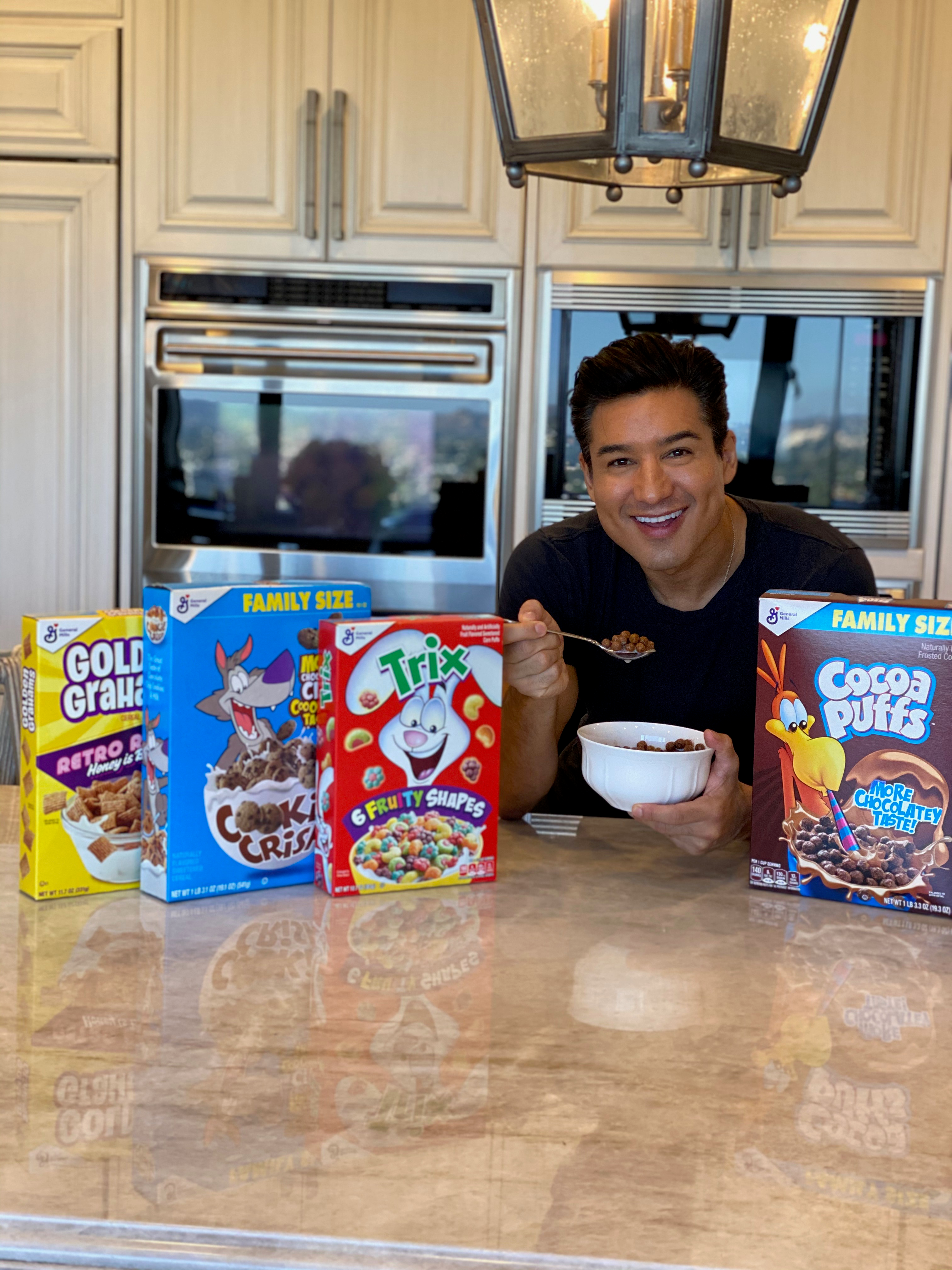Mario Lopez eating a bowl of Cocoa Puffs in his kitchen, smiling