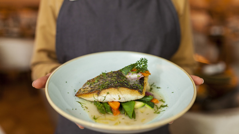 Person holding a plate of fish