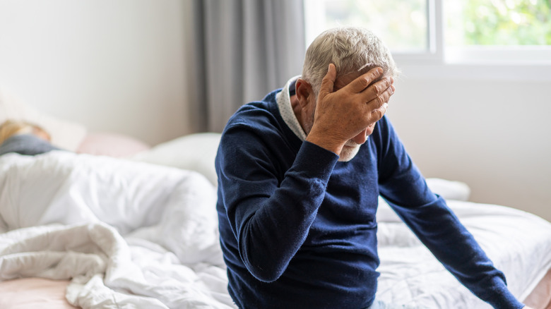 an elderly man holding his head in distress