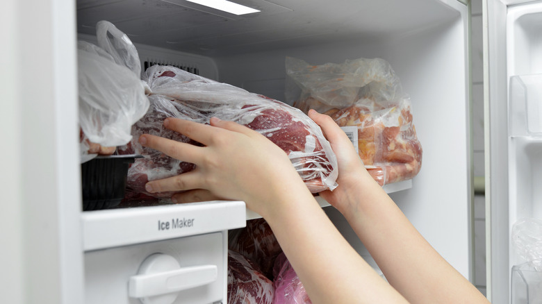 Person takes meat from freezer