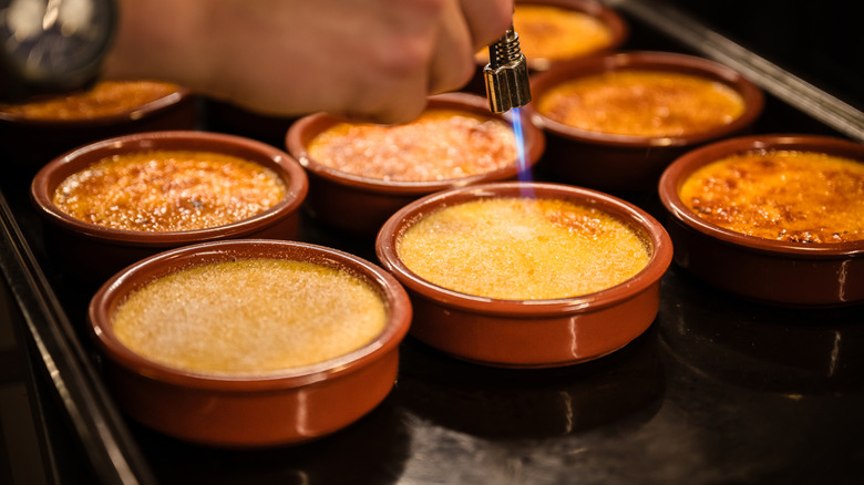 Tray of creme brulee ramekins in the process of getting torched