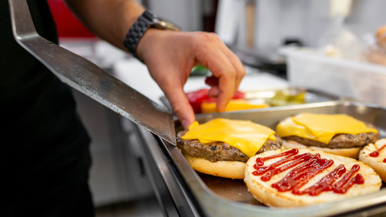 A fast food worker prepares burgers