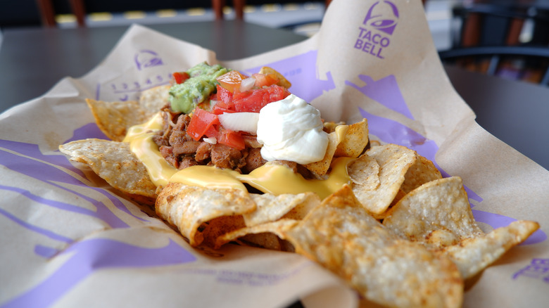 Taco Bell nachos covered in meat, tomatoes, and sour cream