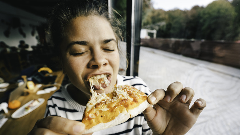 A person eats a slice of pizza