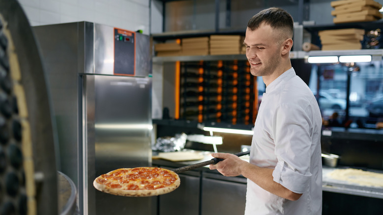 A chef putting a pizza in the oven