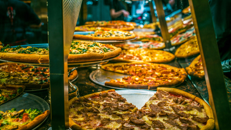 Various pizzas on display behind glass