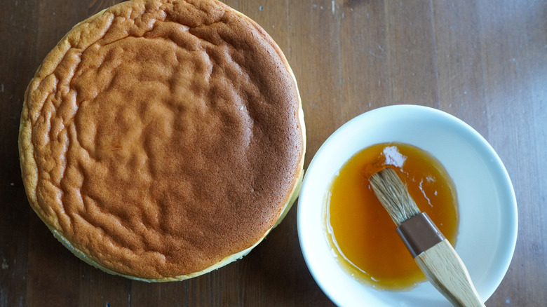 Sponge cake with bowl of glaze and brush for basting