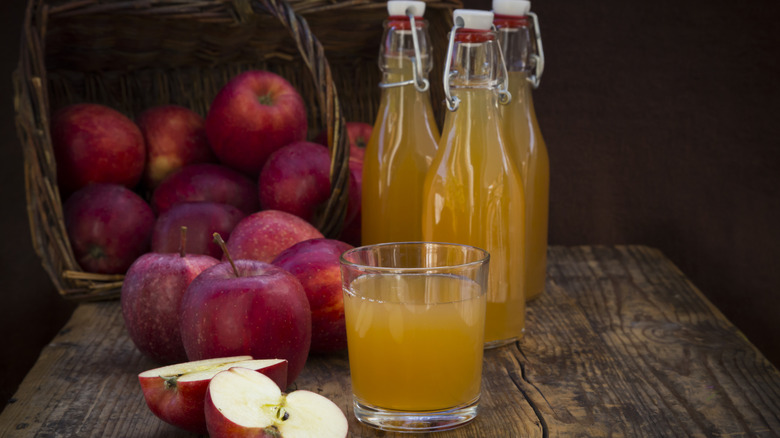 Glass of apple juice with cut apple and bottles of juice