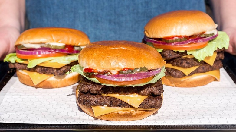 Hands holding tray containing three Wendy's burgers