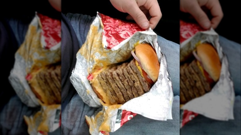 Hands opening wrapping of a T-Rex burger from Wendy's