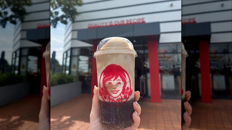 Hand holding Coke Float in front of Wendy's