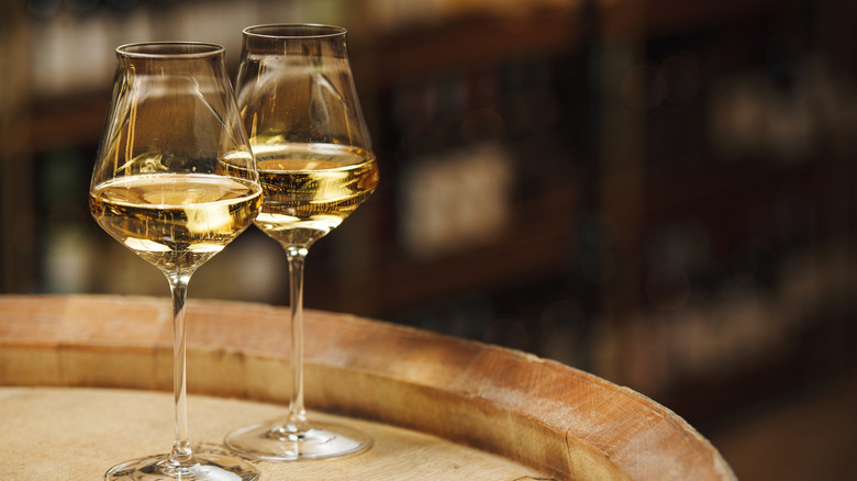 Two glasses of white wine on a barrel