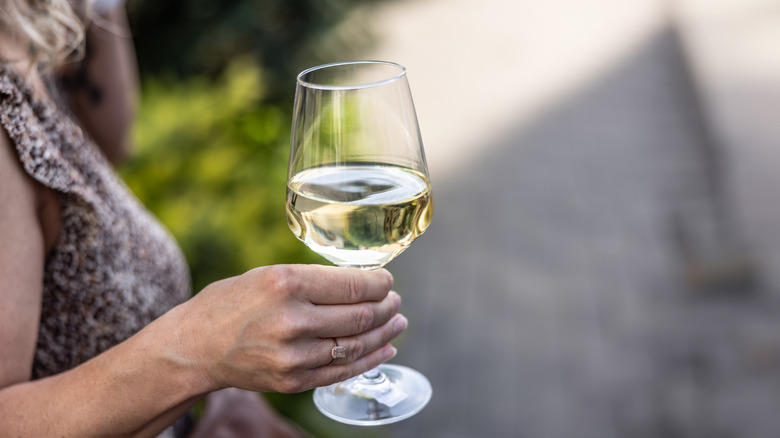 Person holding a glass of white wine