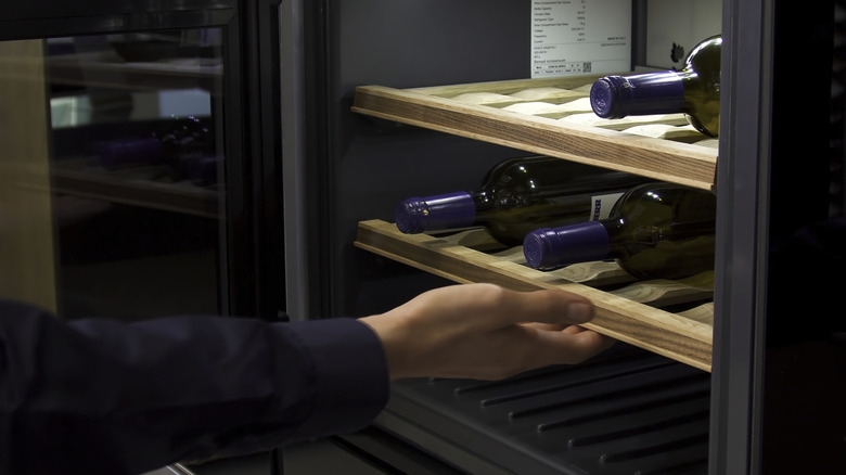 Person reaching into wine fridge