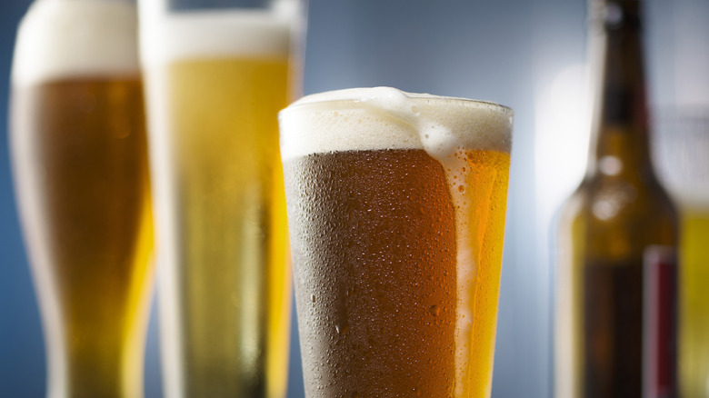 Three foam-topped beer glasses and a bottle