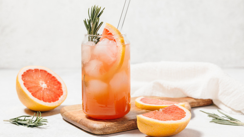 A paloma cocktail surrounded by grapefruit segments