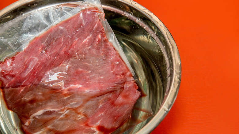 Meat defrosting in a bowl of water