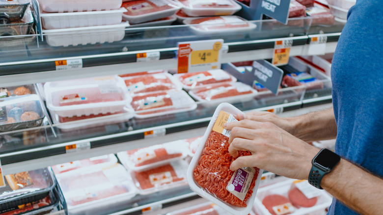 Person looking at a label on ground beef in supermarket