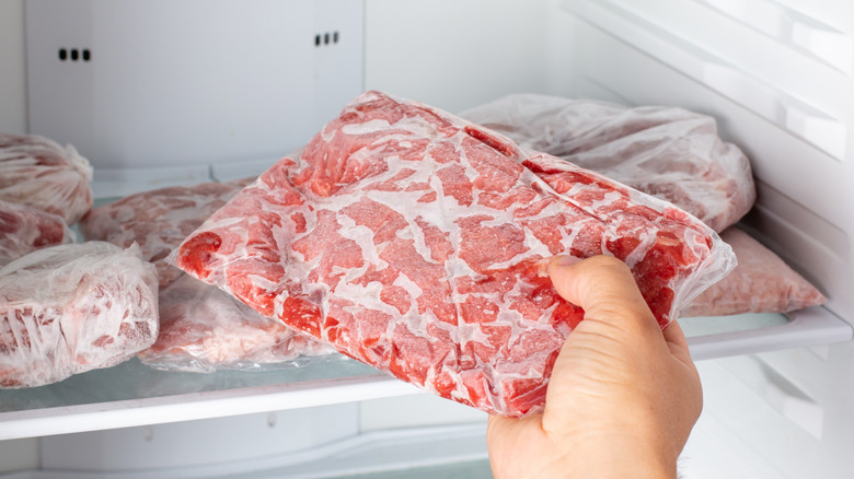 Person taking packet of frozen meat from freezer