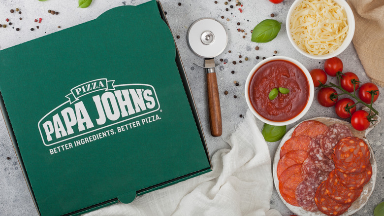 Papa Johns pizza box next to bowls of toppings