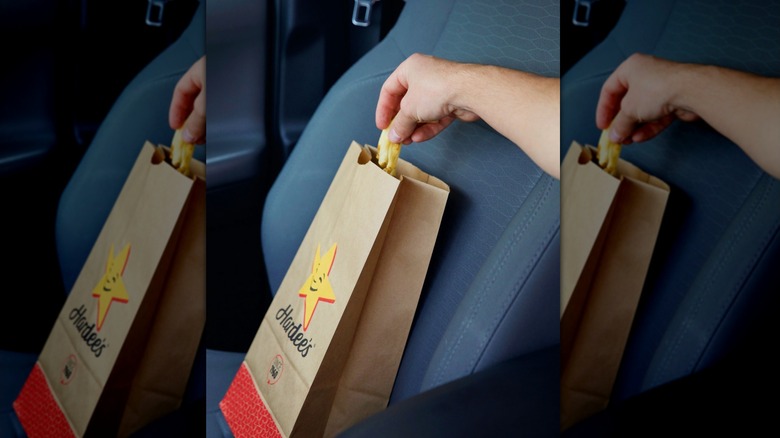 Person pulling fries out of a Hardee's bag