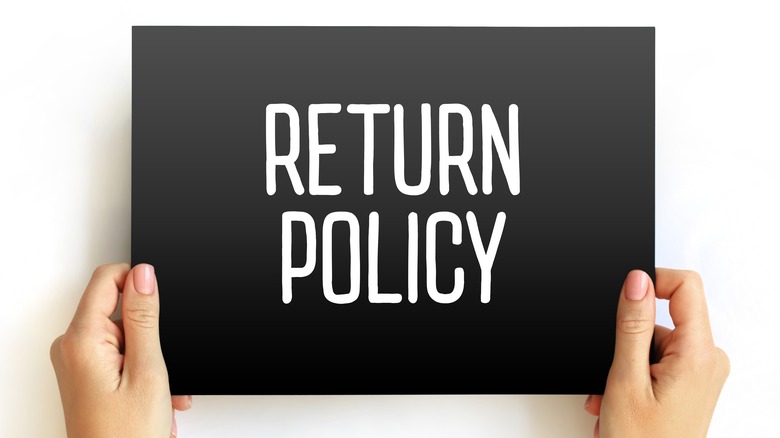 Hands hold a sign saying "return policy"