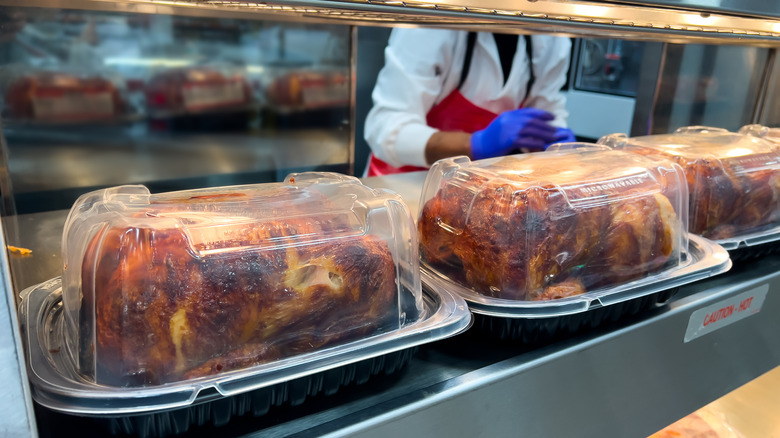 Rotisserie chickens on display in plastic containers