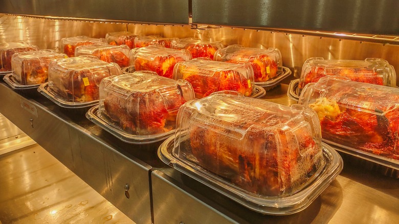 Rotisserie chickens on display under a heating lamp