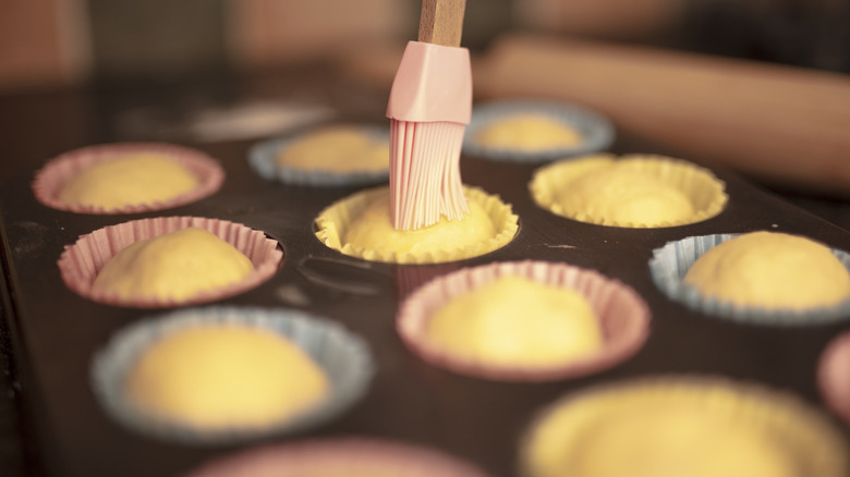 Brushing cupcakes in a cupcake tray