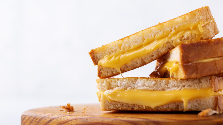 Grilled cheese sandwiches stacked on wooden cutting board