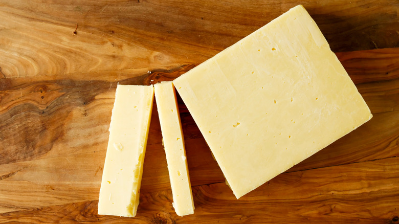 Cut block of cheddar on wooden cutting board