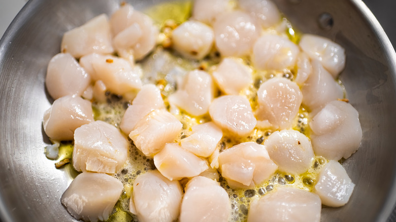 Scallops frying in butter in steel pan