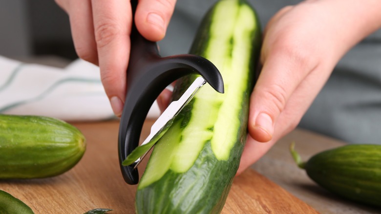 Close-up of hands peeling a cucumber