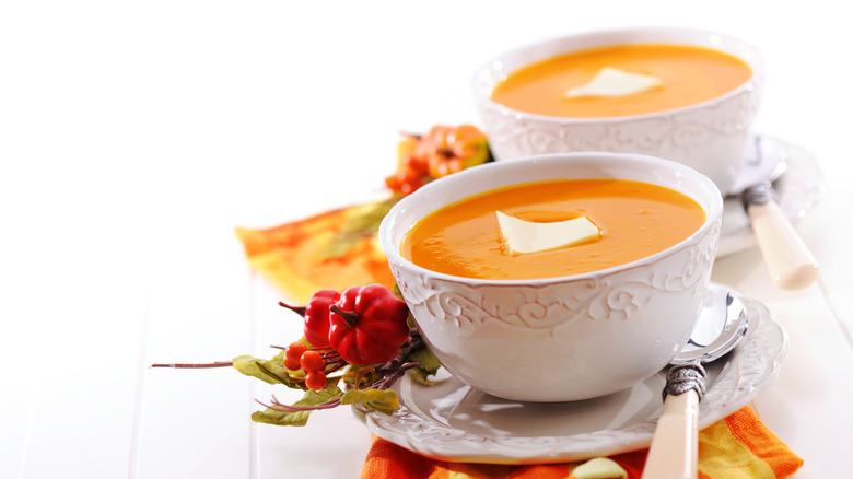 Pumpkin soup in white bowls with butter on top