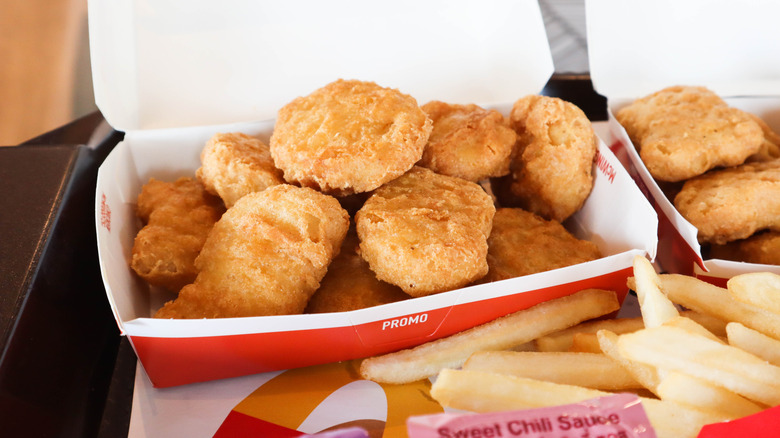 Chicken McNuggets sit in a McDonald's box with fries