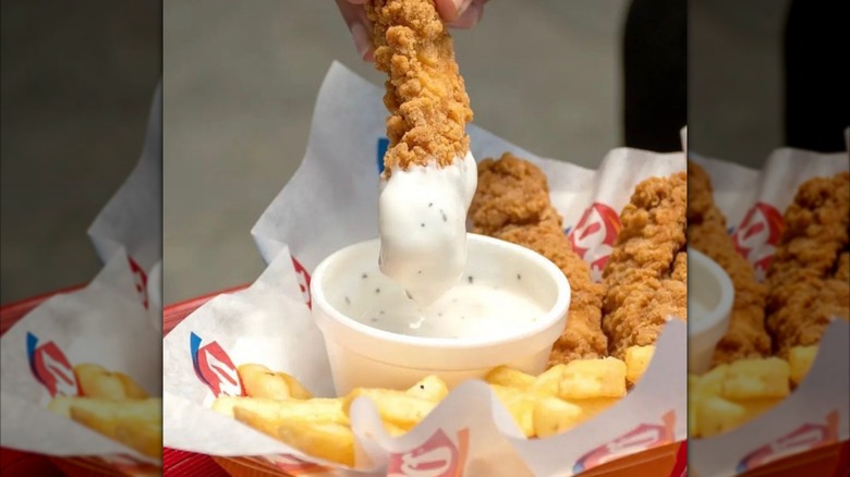 A chicken strip being dipped into gravy at Dairy Queen