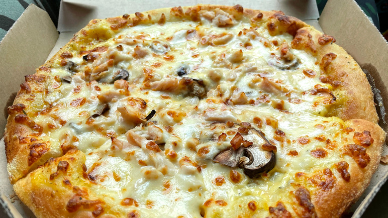 A Domino's pizza with chicken and mushrooms in a box