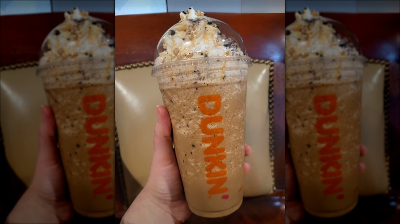 A hand holding Dunkin' Butter Pecan Frozen Coffee