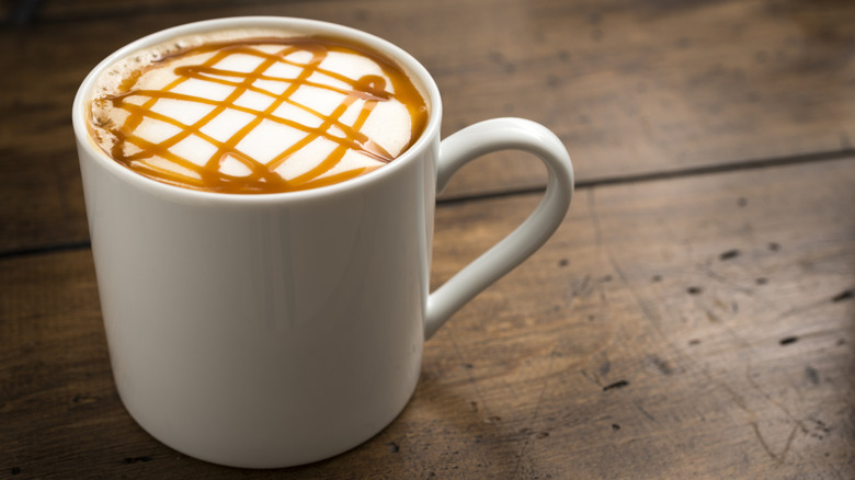 A cup of coffee with caramel drizzle on a wooden table