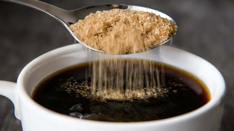 Raw sugar poured into a cup of black coffee