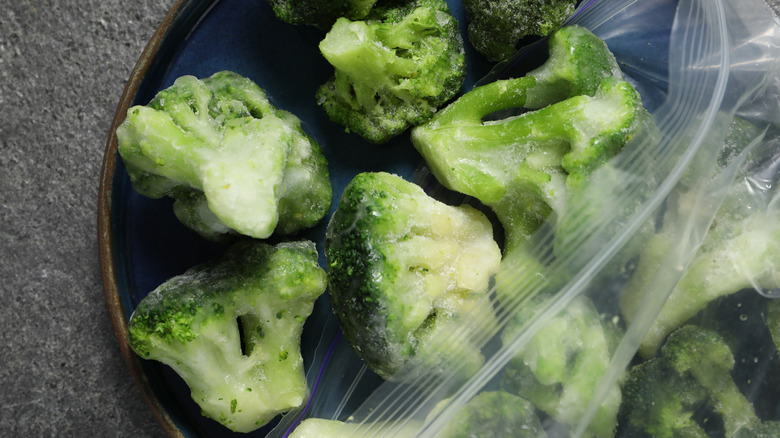 Frozen broccoli spilling out of plastic bag onto plate