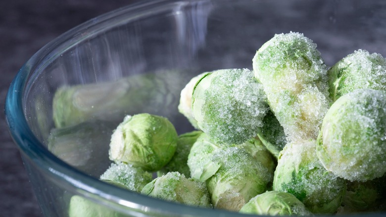 Glass bowl full of frozen whole Brussels sprouts