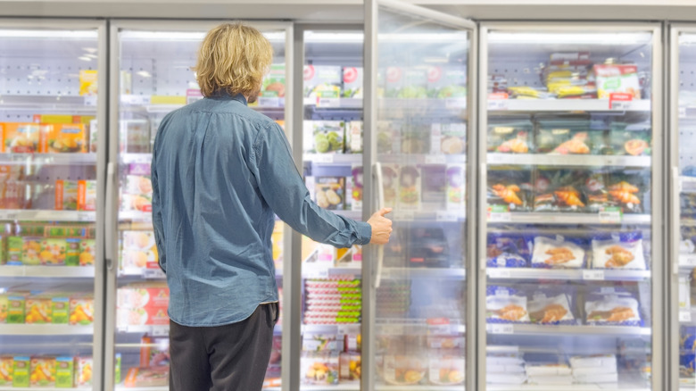 Person perusing frozen foods in grocery store