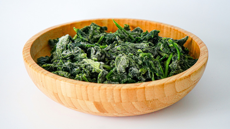 Wooden bowl full of frozen spinach leaves